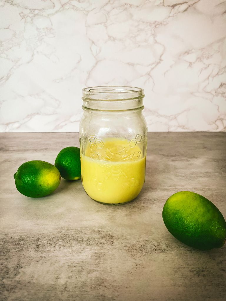 mason jar filled with lime curd and 3 limes