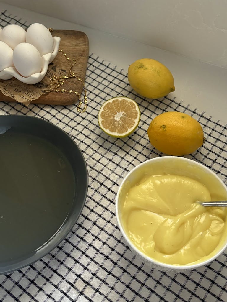 Top view of a table setting with lemon curd, eggs, and lemons.