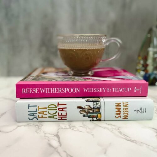 glass mug with pistachio iced coffee on top of a stack of books