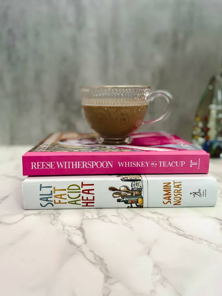 glass mug with pistachio iced coffee on top of a stack of books